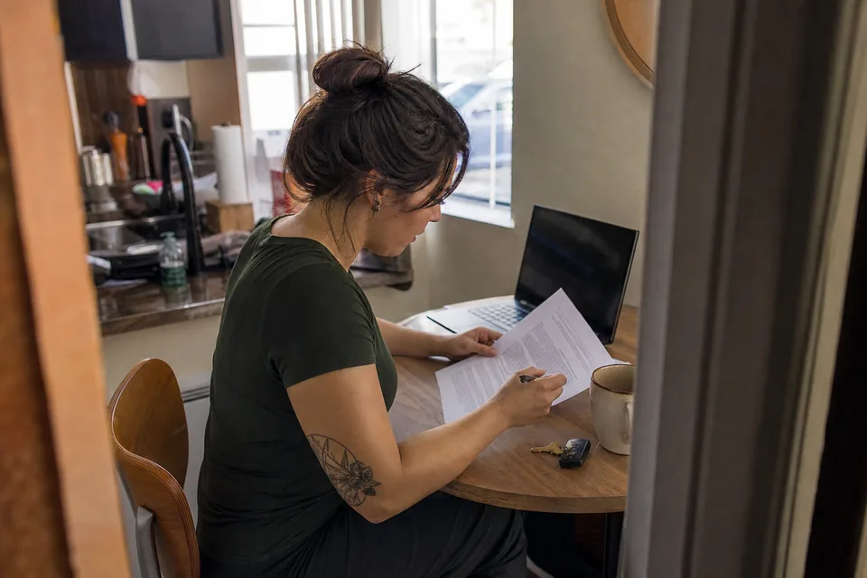 Resident reading a lease addendum about a rent reporting subscription at her kitchen table